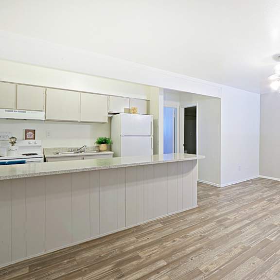 A kitchen with a white counter and a white fridge.
