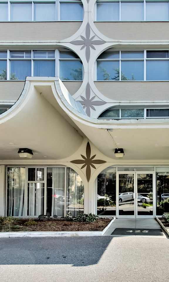 A modern building with a white facade and a large glass window.