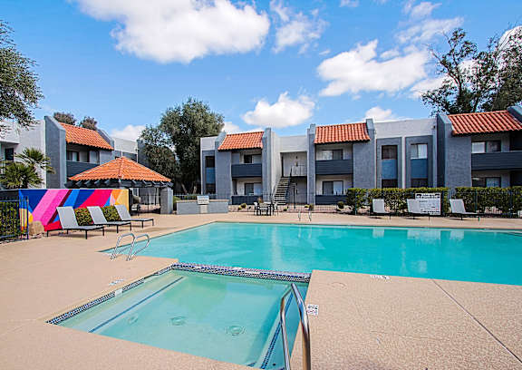 A swimming pool in front of a building with a colorful mural on the fence.