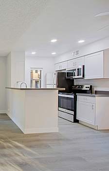 A kitchen with white cabinets and a microwave on top of the counter.
