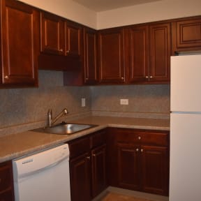 an empty kitchen with white appliances and wooden cabinets