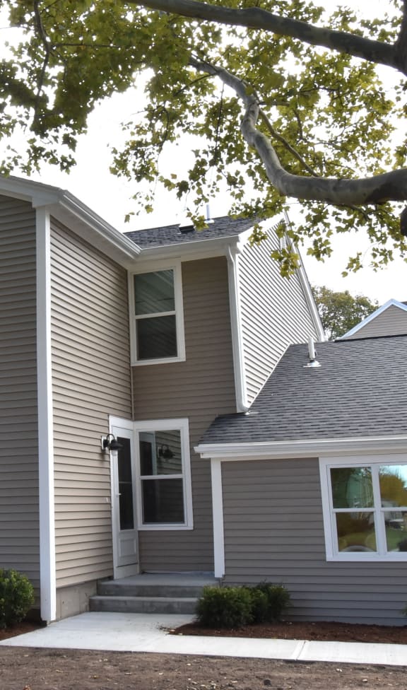 a gray house with a tree in front of it