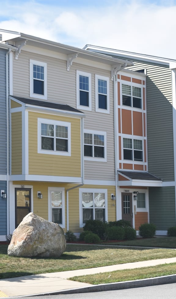 a row of townhomes with a large rock in front of them