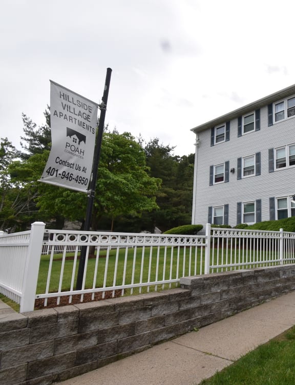 an apartment building with a white fence and a sign in front