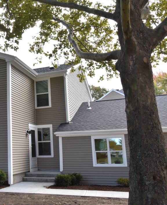 a gray house with a tree in front of it