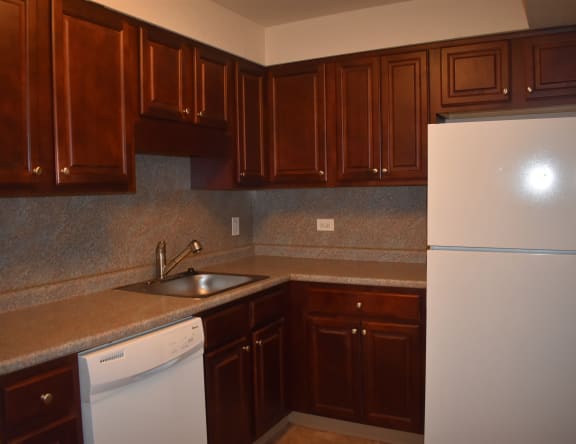 an empty kitchen with white appliances and wooden cabinets