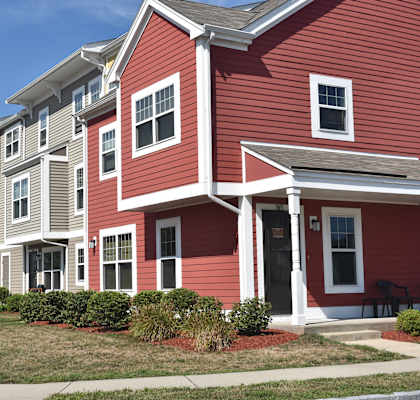 a row of red houses with white siding and a lawn