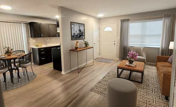 A modern living room with a kitchen area in the background.