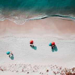 three people on the beach with umbrellas