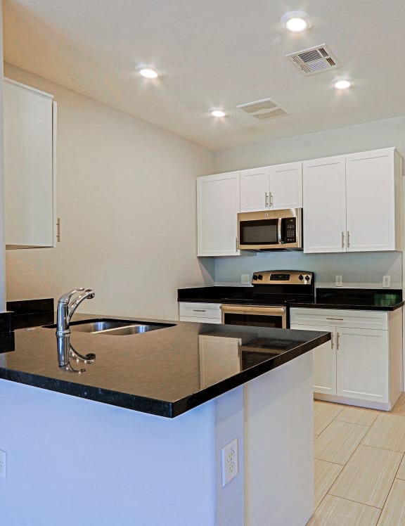 a kitchen with white cabinets and black countertops