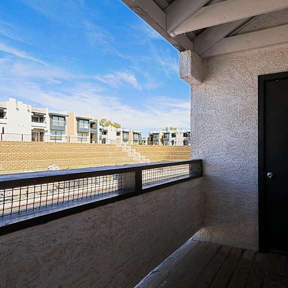 a balcony with a door and a view of a baseball field