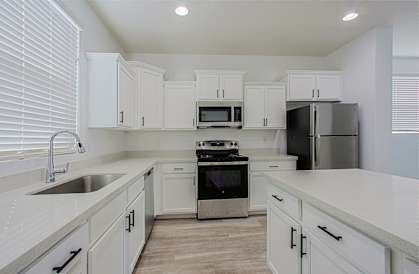 an empty kitchen with white cabinets and stainless steel appliances