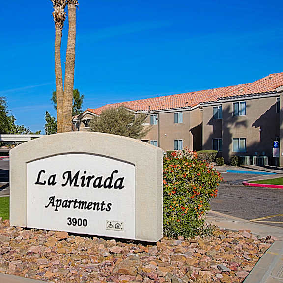 A sign for La Mirada Apartments is in front of a building.