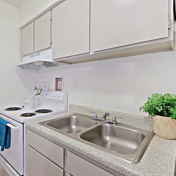 A kitchen with a stove, sink and cabinets.