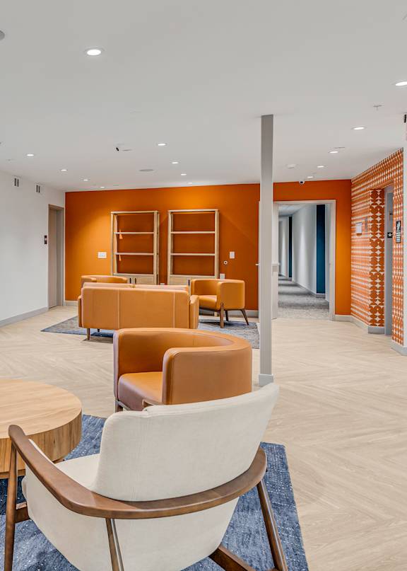 A room with orange chairs and a blue rug.