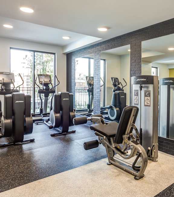 A gym with a variety of equipment including treadmills, weights, and exercise machines.