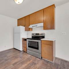 a kitchen with wood flooring and white appliances and wooden cabinets