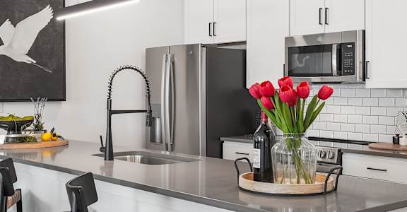 A kitchen with a black and white painting on the wall.