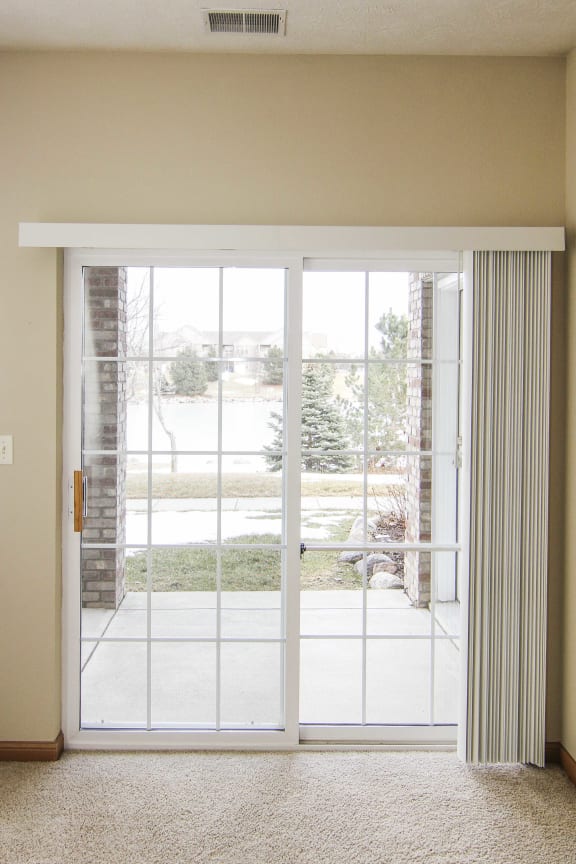 Sliding glass door with vertical blinds, looking out onto patio.