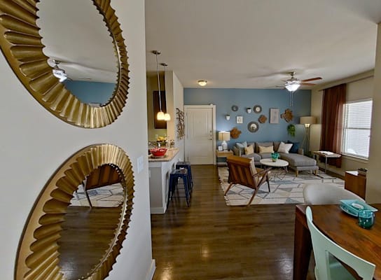 A modern living room with a wooden floor and a large mirror on the wall.