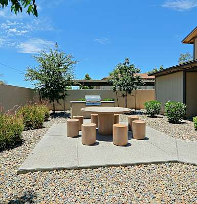 a patio with a table and chairs in front of a house