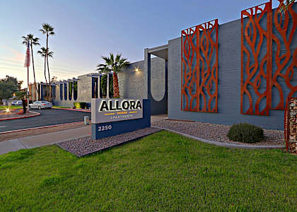 The image shows the exterior of Allora Apartments at sunset.