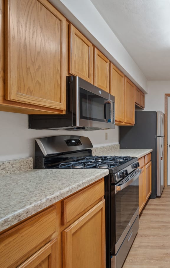 a kitchen with wood cabinets and granite counter tops and a stove and microwave