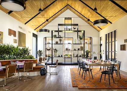 A modern dining room with a wooden ceiling and a large table surrounded by chairs.