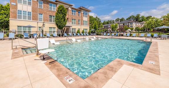 A large swimming pool in front of a multi-story apartment building.