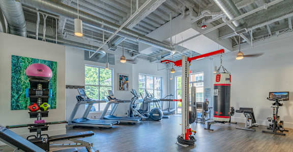 A gym with a variety of equipment including treadmills, weights, and exercise machines.
