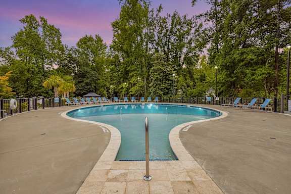 A large outdoor swimming pool surrounded by trees and lounge chairs. at Forest Hills Racquet Club, Georgia
