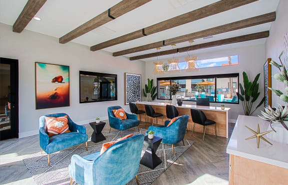 a living room with blue chairs and a table and a large window at The Peak at Oro Valley Apartments, Arizona, 85704