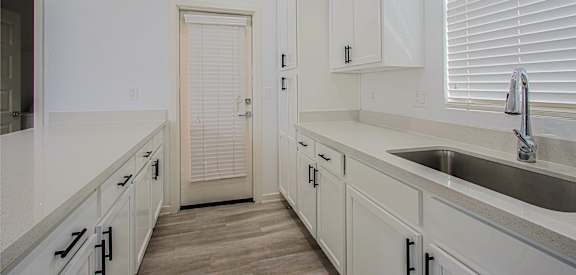 an empty kitchen with white cabinets and a sink