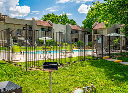 A black fence surrounds a pool and a building.