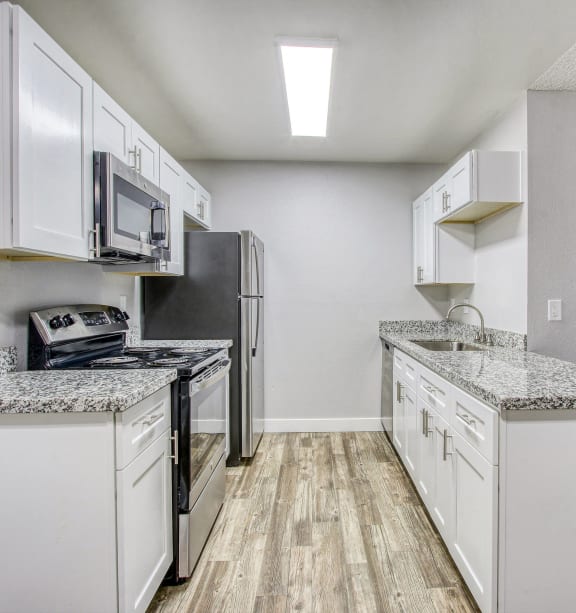 an empty kitchen with white cabinets and a stainless steel refrigerator