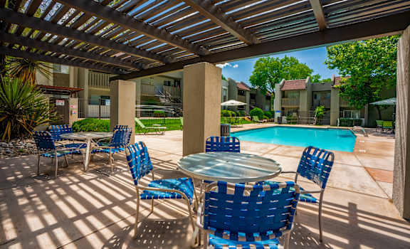 A patio with blue chairs and a table under a roof.