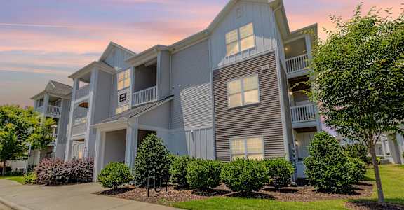 A modern apartment building with a well-maintained lawn and trees in front. at Concord Ridge Apartments, Concord, NC, 28027