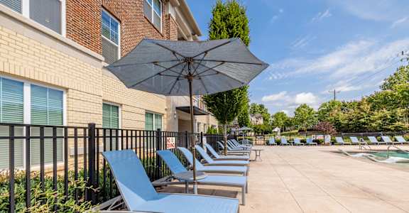 A row of blue lounge chairs are arranged on a patio.
