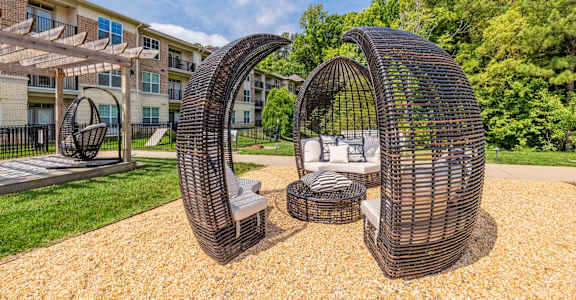 A modern outdoor seating area with two large woven structures and a small table.