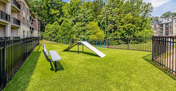 A park with a slide and bench in the foreground and apartment buildings in the background.