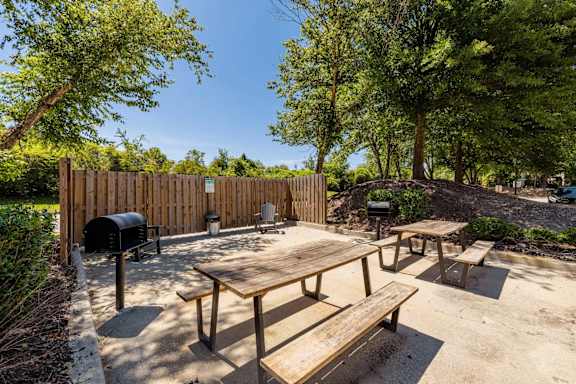 A wooden picnic table with benches is set up in a backyard. at Sanctuary Apartments & Townhomes, Augusta
