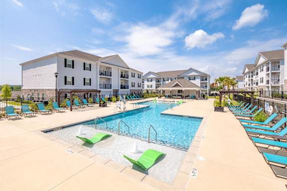 A large swimming pool with lounge chairs and apartment buildings in the background at The Vista Apartments & Townhomes, South Carolina, 29851