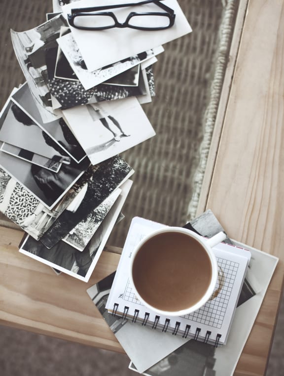 a cup of coffee and a pile of photographs on a table