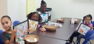 Children sitting around table with artwork