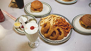 a table topped with a plate of onion rings and fries