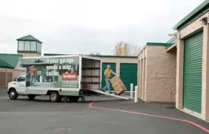 A white truck is parked in front of a garage.