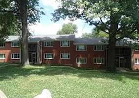 A red brick building with a tree in front.