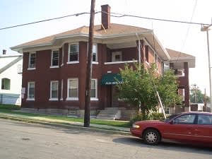 A red car is parked in front of a red brick building.