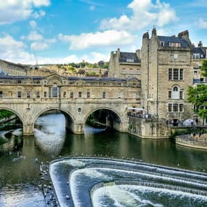A stone bridge over a river with a building in the background.