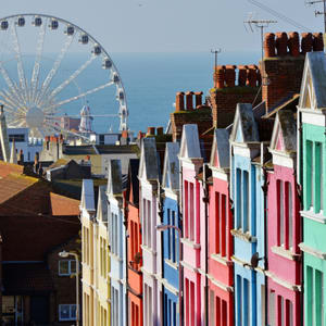 A row of brightly colored houses with a Ferris wheel in the background.